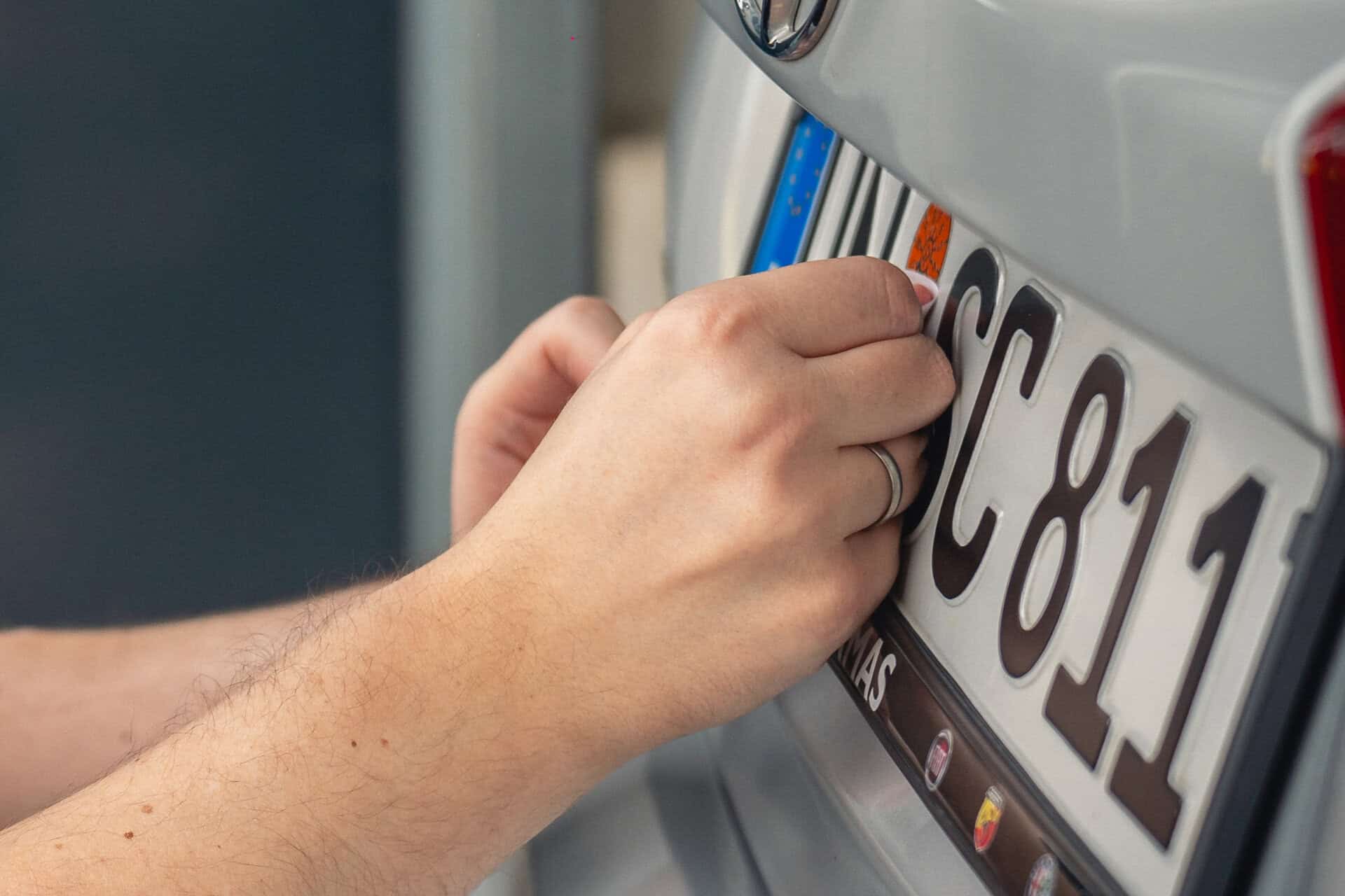 KÜS Prüfingenieur klebt neue HU-Plakette auf das PKW-Kennzeichen in Selm