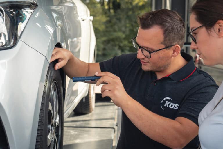 KÜS-Prüfingenieur mit Kundin am Auto