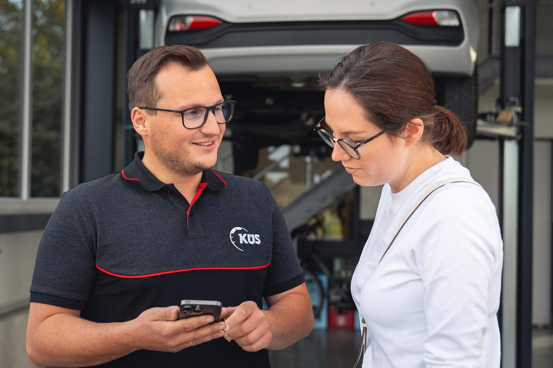 Prüfingenieur zeigt Kundin i-kfz app